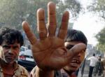 A migrant worker brings up his hand to shield himself from being photographed while waiting for casual job openings at a street corner in a public labour market in Mumbai November 24, 2008. REUTERS/Arko Datta